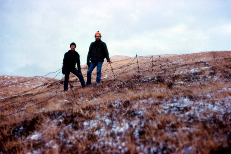 Adak, Shagak Bay, WWII barb-wire fence with bungi stakes, OT Tyson Joye & OT Mike Schleis - Jan. 1974  Photo by Michael Hein